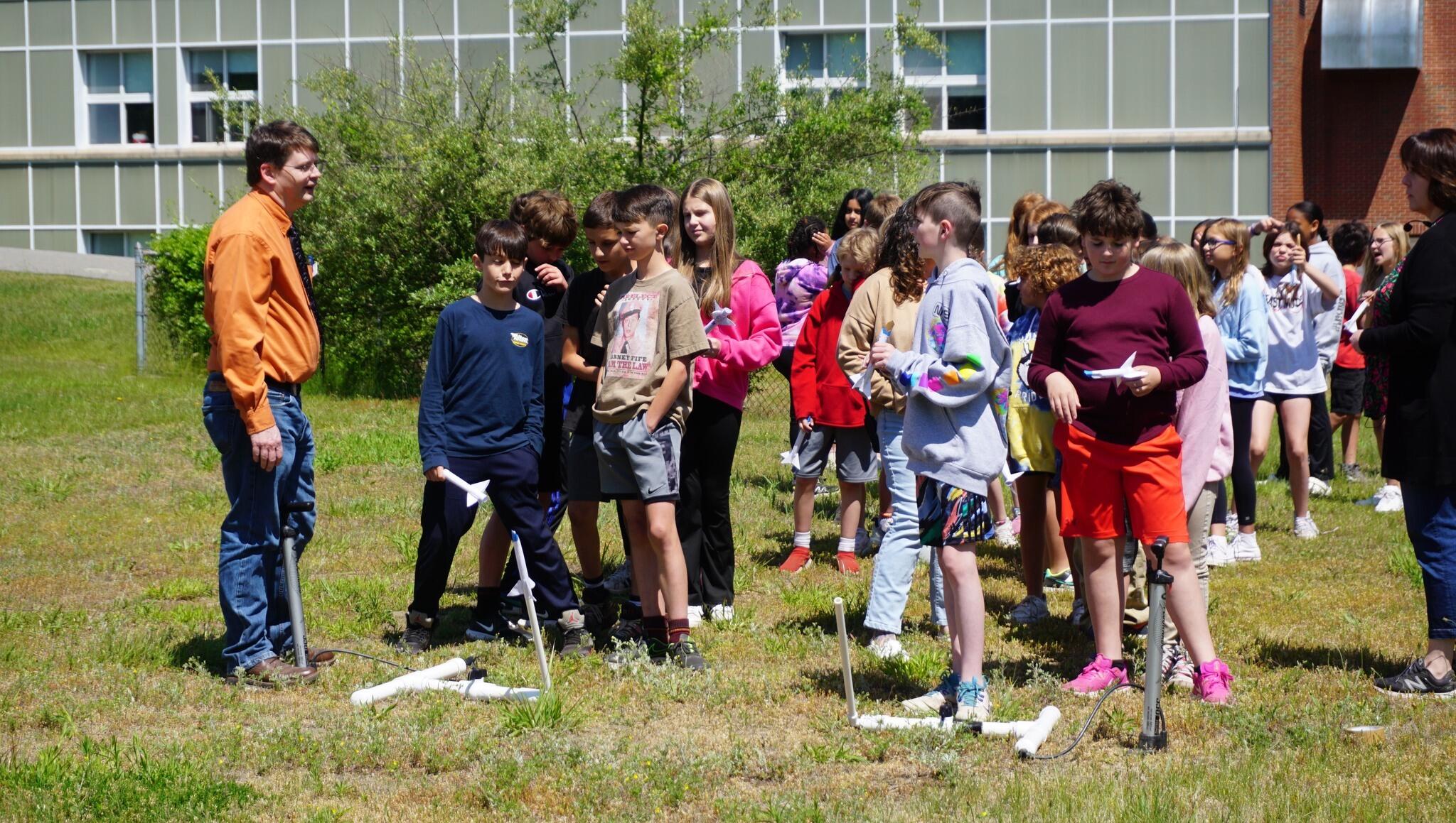 Students outside school building launching rockets